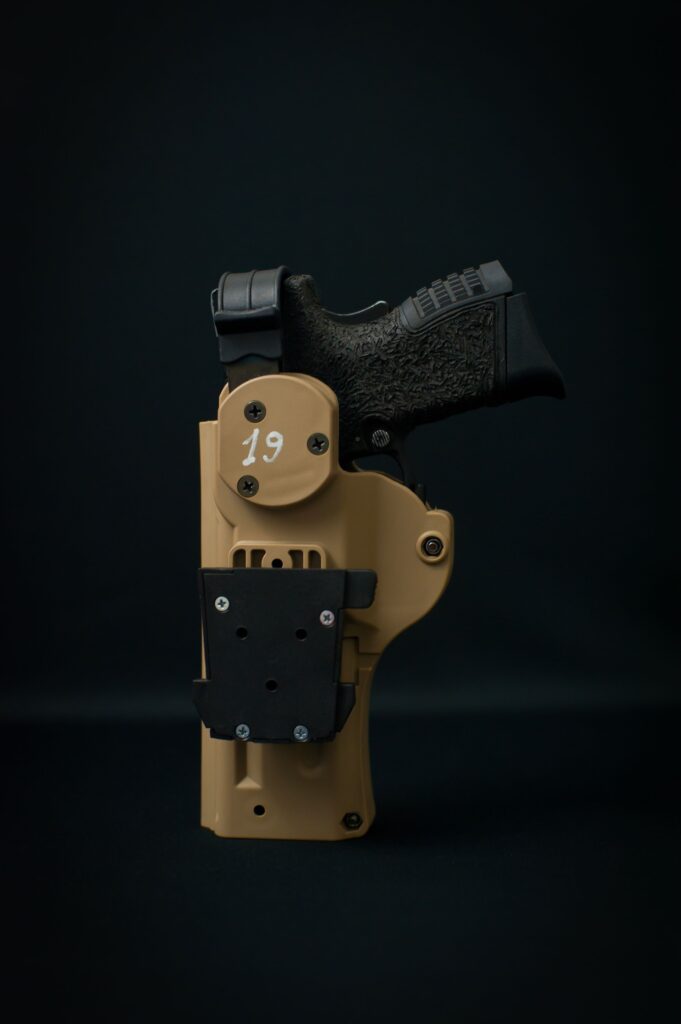 Black handgun secured in a tan concealed carry holster