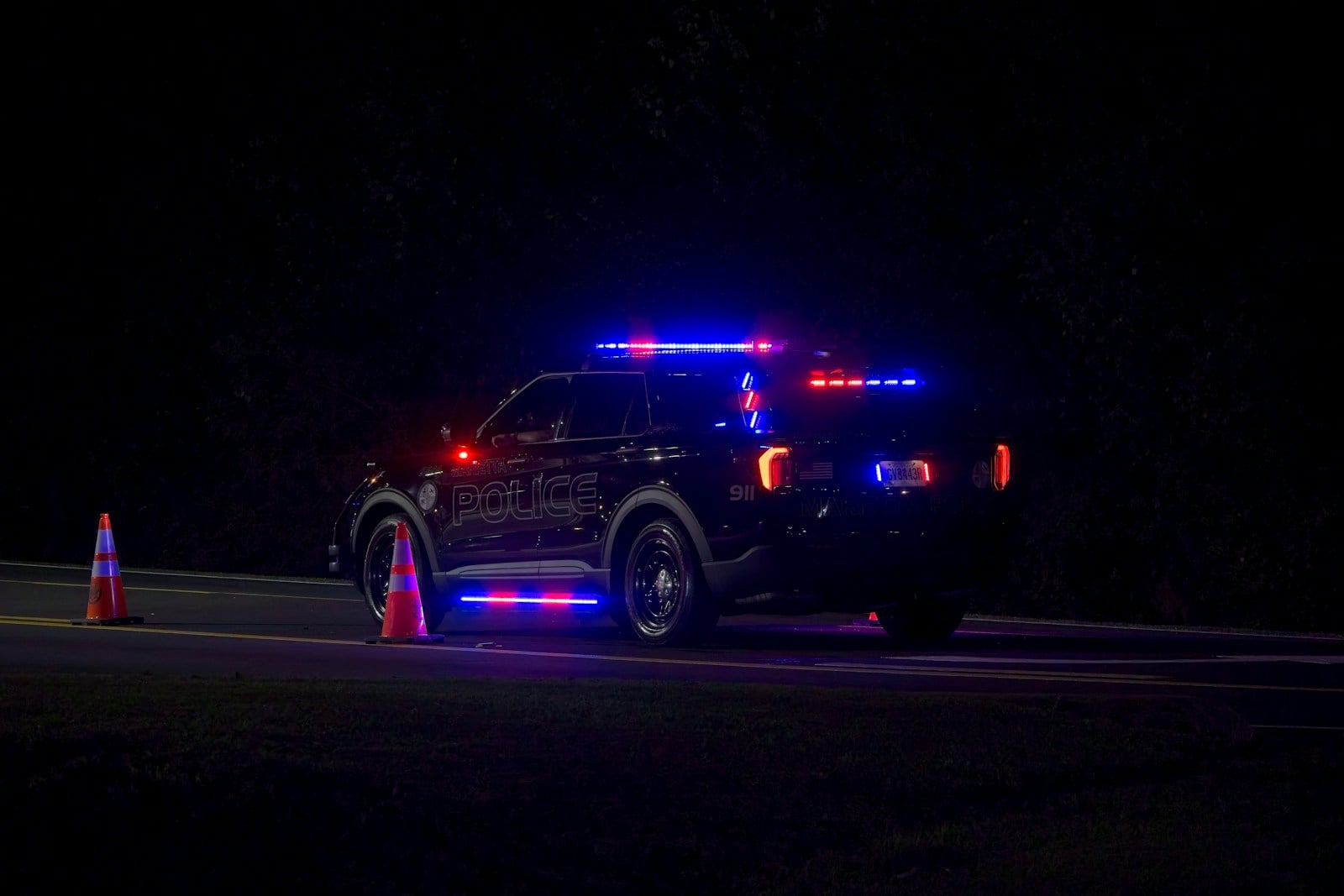 Police vehicle with flashing red and blue lights on a dark road during a traffic stop