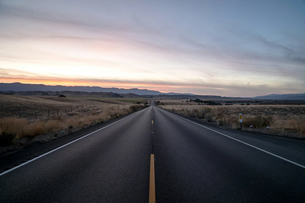 Open road stretching through hills at sunset