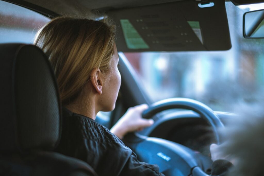 Woman sitting in the driver seat holding the steering wheel